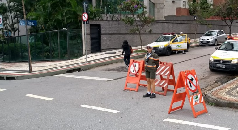 Agentes de trânsito e sinalizadores de via interditada, durante o dia. 