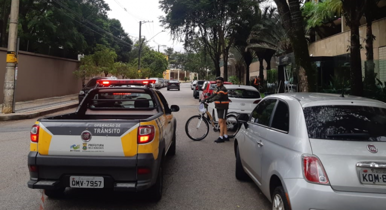 Veículo da BHTrans circulando em rua, junto a outros carros, no trânsito, durante o dia. 