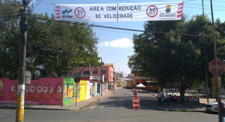 O bairro Confisco recebe, a partir desta semana, o projeto Zona 30, que limita a velocidade para veículo em vias locais, a 30km/h. Foto: Divulgação PBH Rua semi-interditada com sinalização da BHTrans e um cartaz com os dizeres: "30 km. Área com redução de velocidade".
