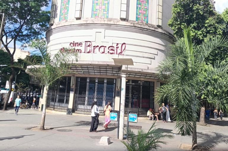 Fachada do Cine Brasil, com pessoas passando na frente, em dia ensolarado.
