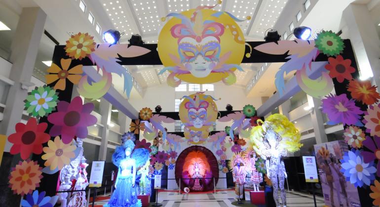 salão interno da prefeitura de belo horizonte com exposição de fantasias carnavalescas, uniformes de baterias de blocos e escolas e até mesmo um carro conversível, como os utilizados nos desfiles de Carnaval de antigamente