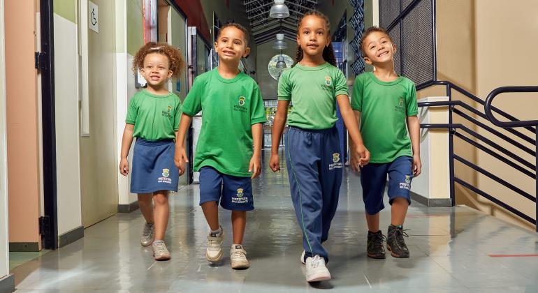 quatro crianças caminham no corredor de um escola
