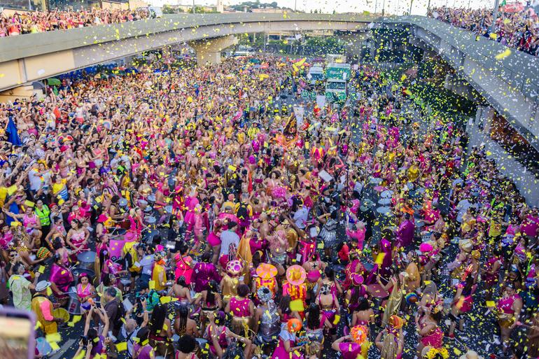 Cadastramento de blocos para o Carnaval de BH 2027 começa nesta terça-feira (18) Imagem do bloco carnavalesco Então, Brilha! em desfile na Avenida dos Andradas, durante o Carnaval de Belo Horizonte 2026. Elementos do cortejo destacam as cores rosa e amarela.