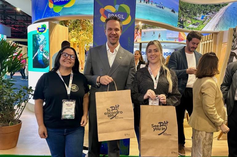 Da esquerda para a direita, a assessora da Gerência de Promoção Turística da Belotur, Márcia de Carvalho; o presidente da Embratur, Bruno Reis; e a assessora de Planejamento do Gabinete da Belotur, Tamara Peixoto, posam para foto durante a ABAV Expo 2026. Bruno Reis segura um kit promocional de Belo Horizonte, com destaque para a marca “Te Encontro em BH”. Da esquerda para a direita, a assessora da Gerência de Promoção Turística da Belotur, Márcia de Carvalho; o presidente da Embratur, Bruno Reis; e a assessora de Planejamento do Gabinete da Belotur, Tamara Peixoto, posam para foto durante a ABAV Expo 2026. Bruno Reis segura um kit promocional de Belo Horizonte, com destaque para a marca “Te Encontro em BH”.