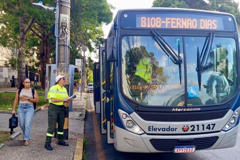 Agente da BH, usando uniforme, aborda coletivo da linha 8108 - Dernão Dias, em via pública, posicionada de frente para a porta do coletivo