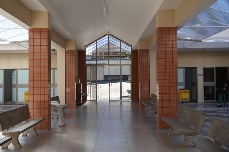 Imagem interna da Capela Velório do Barreiro, com as colunas na entrada do equipamento público, e bancos compondo o cenário.