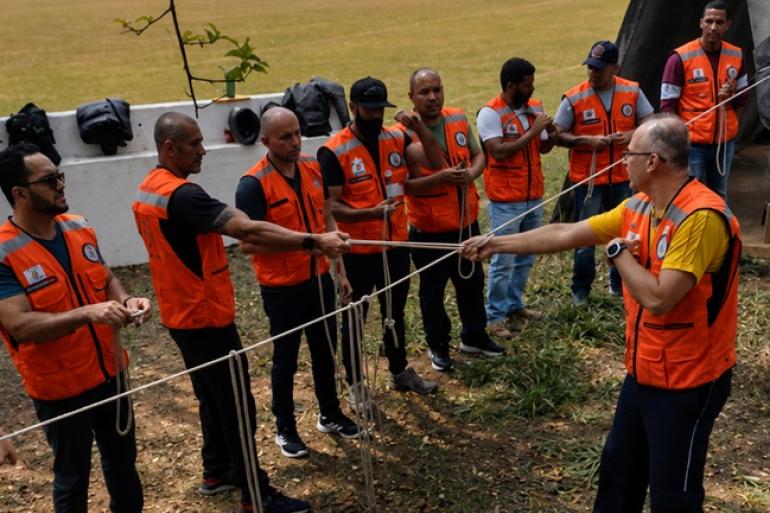 Servidores da Defesa Civil de BH, usando coletes laranjas da instituição, participam de treinamento com cordas