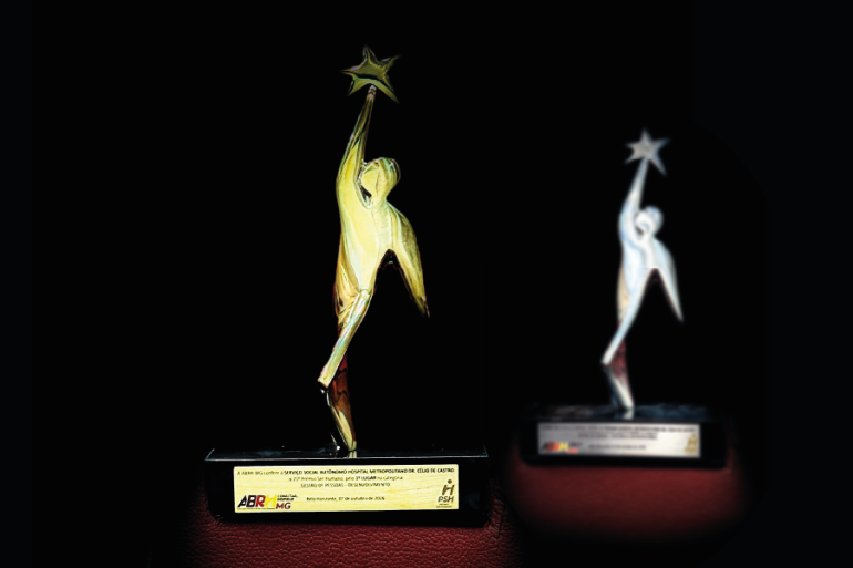 Hospital Célio de Castro é destaque em duas categorias do Prêmio Ser Humano com projetos que aprimoram a gestão de pessoas Imagem do troféu do Prêmio Ser Humano da ABRH-MG, composta por uma escultura estilizada de uma figura humana com o braço levantado para alcançar uma estrela. No primeiro plano a imagem é dourada e no segundo plano a imagem é prata.