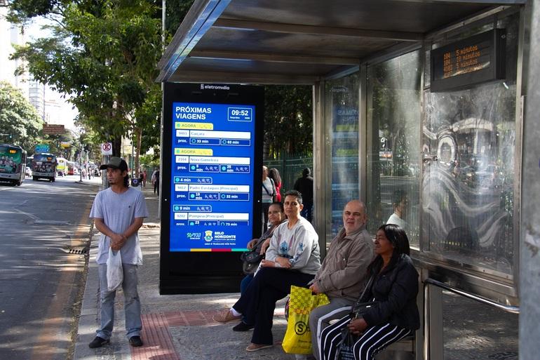 Cinco pessoas aguardam ônibus em ponto da Avenida Afonso Pena