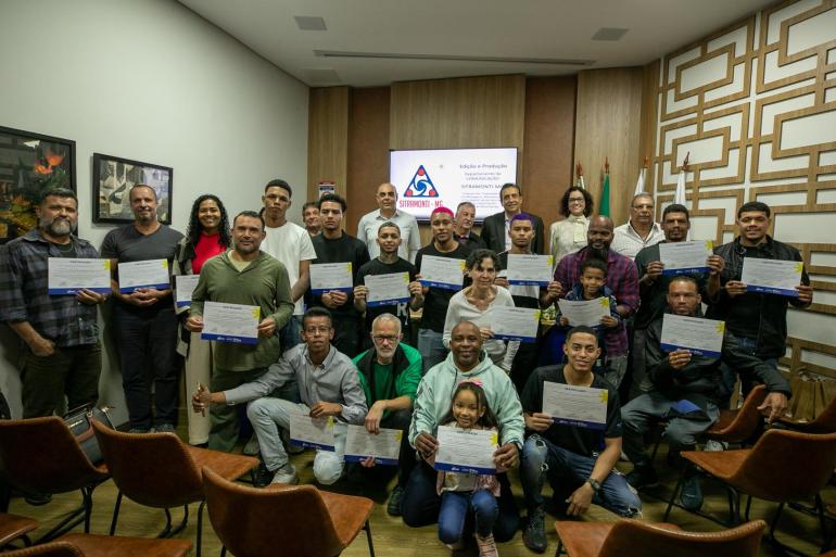 Prefeitura de Belo Horizonte forma mais duas turmas do curso de auxiliar de solda Grupo de formandos à frente e autoridades da mesa da solenidade posicionadas atrás.