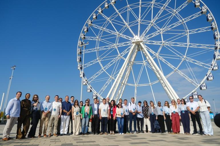 Programas de mitigação climática, drenagem e urbanização da PBH são apresentados em Fórum de Prefeitos do BID na Colômbia Representantes de diferentes cidades posam para foto coletiva em frente a uma grande roda-gigante. O grupo está reunido em uma área aberta, sob céu azul e tempo ensolarado.
