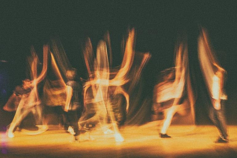 PBH lança edital de R$ 6,3 milhões para projetos culturais e ações continuadas Fotografia de longa exposição, granulada, de um palco no qual cinco bailarinos movimentam-se, criando rastros e efeitos de sobreposição de seus corpos em movimento, num fundo escuro.