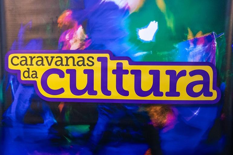 Arte com fundo em policromia em tons de verde, azul e vermelho traz o nome Caravana da Cultura.