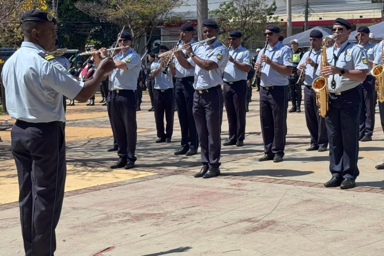 Banda da Guarda Municipal de BH recebe novos instrumentos Banda da Guarda Civil Municipal de Belo Horizonte se apresenta em praça pública sob regência de maestro, que está de costas na imagem, tendo em frente vários músicos tocando instrumentos de sopro. Todos estão uniformizados.