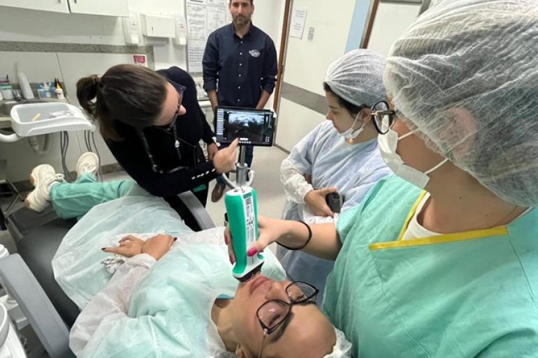 Hospital Odilon Behrens qualifica assistência em saúde bucal com aquisição de novo ultrassom portátil Profissionais de saúde bucal prestam atendimento em paciente deitada na cadeira