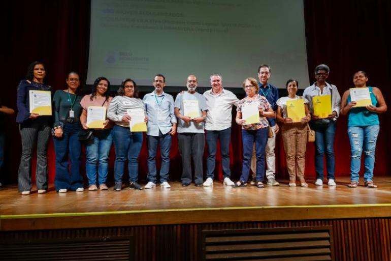 Prefeito Álvaro Damião e presidente da Urbel estão ao lado de oito moradores de vilas e favelas que receberam títulos de regularização fundiária.