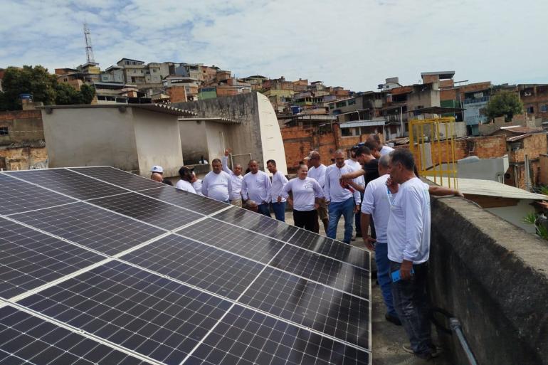 Escola Profissionalizante da PBH oferece pela 1ª vez em um mesmo dia aulas para turmas de dois cursos Imagem de alunos do curso profissionalizante trajando camiseta branca em um terraço analisando placas de energia fotovoltaica
