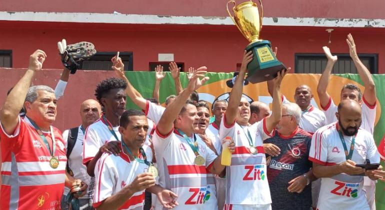 Jogadores do time do Letícia seguram troféu de campeão da categoria Master 50 da Copa Centenário