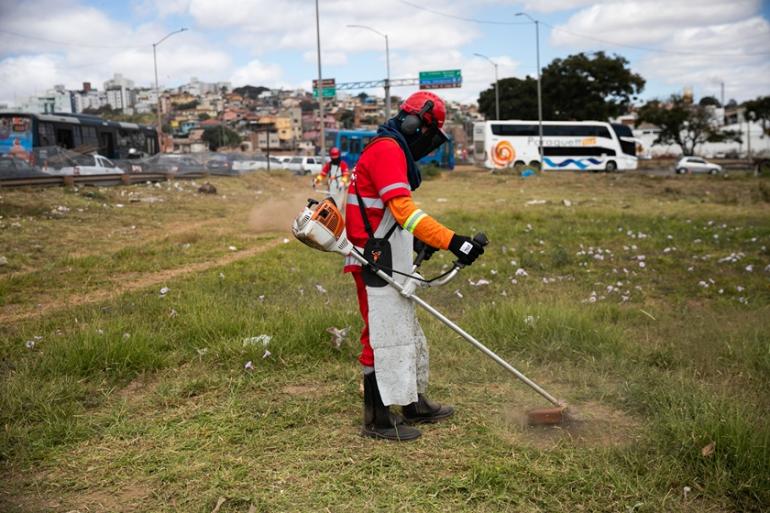 Trabalhador usando equipamento e roupa da PBH faz a manutenção às margens do Novo Anel