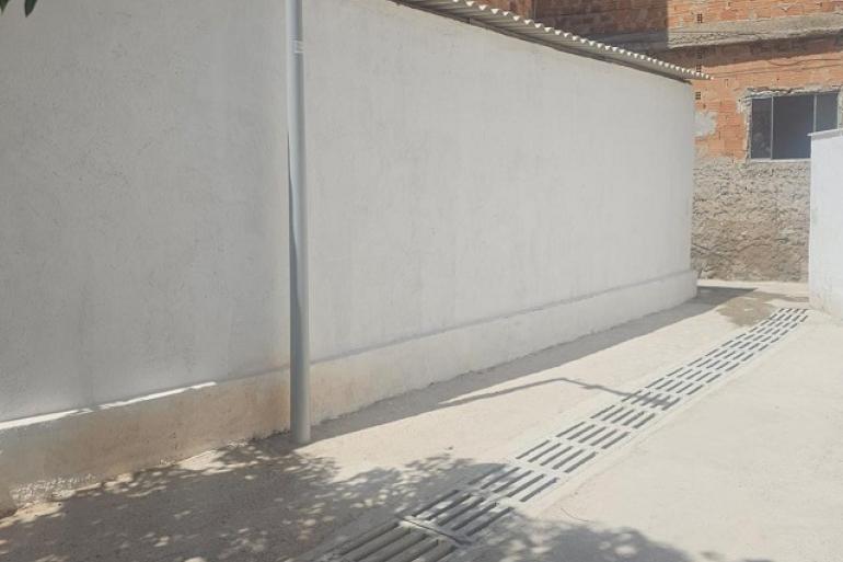 Obras de urbanização em fase final amplia infraestrutura da Vila Cabana do Pai Tomás imagem mostra o trecho de uma rua com um muro branco do lado esquerdo e uma grade no piso.