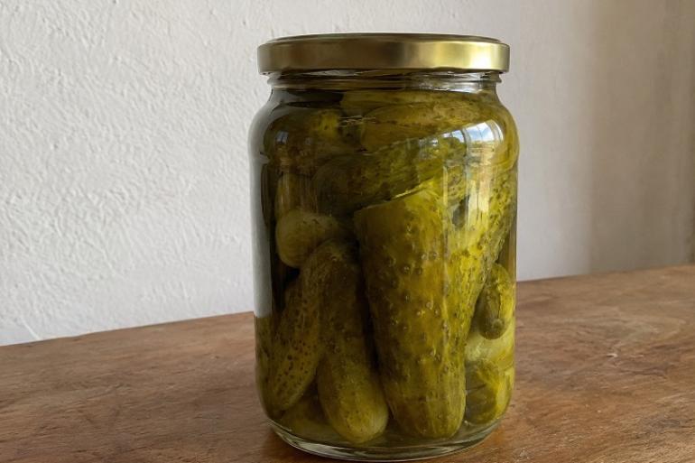 Prefeitura de Belo Horizonte oferece oficina gratuita inédita de produção de picles Imagem mostra um vidro com conserva de pepino disposto em cima de uma mesa de madeira.
