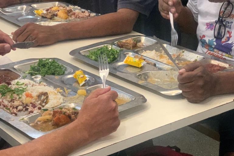 Imagens de pessoas se alimentando com bandeijão, segurando talheres, em unidade da Segurança Alimentar e Nutricional da PBH
