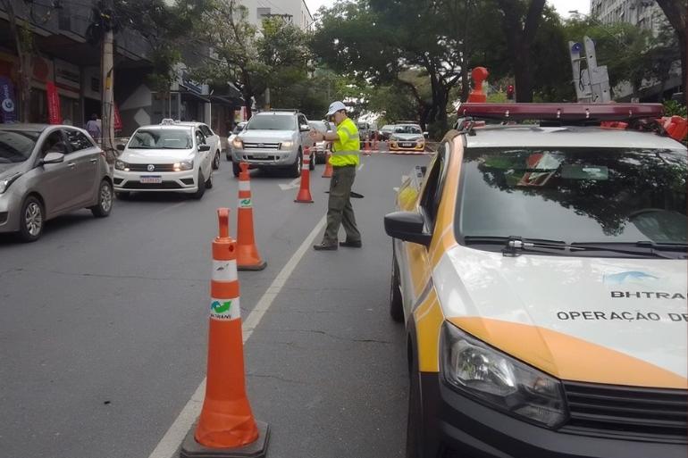 BHTrans realiza operações de trânsito para eventos na capital neste final de semana Imagem mostra um funcionário da BHTrans controlando o trãnsito. De um lado há uma viatura e do outro carros em movimento.