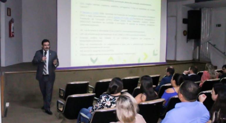 Homem palestra para cerca de nove pessoas. 