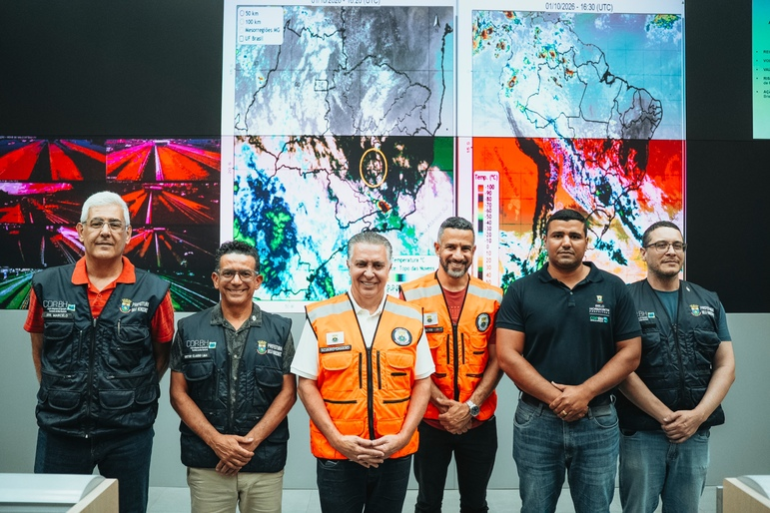 Após onda de calor, PBH alerta para chegada de frente fria e risco de tempestades e granizo A imagem mostra seis homens perfilados em frente a várias telas que mostram mapas meteorológicos de Minas Gerais. Entre eles está o prefeito Álvaro Damião, que veste colete na cor alaranjado, na Defesa Civil de BH