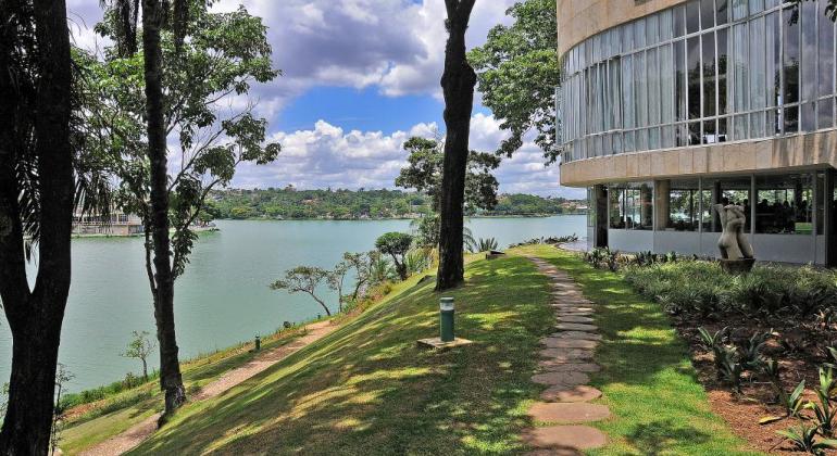 Lateral do Museu de Arte da Pampulha, com árvores e lagoa ao fundo.