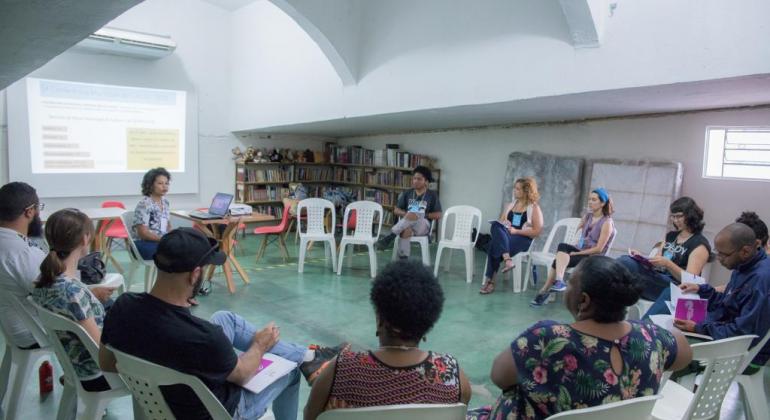 Grupo está sentado em círculo em cadeiras de plástico