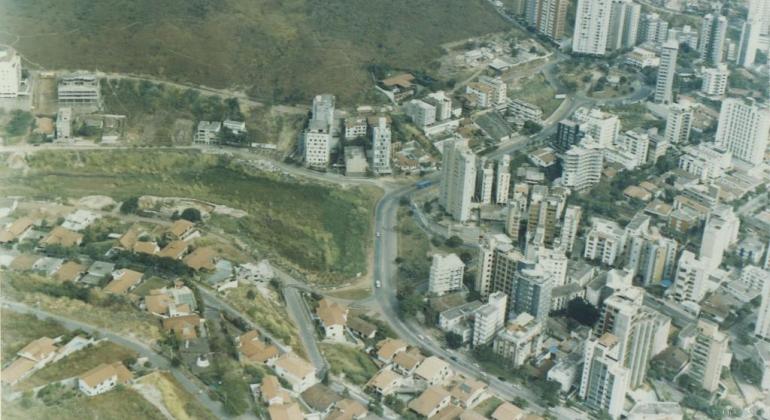 Foto aérea do Bairro Sion na década de 1990, com prédios e área verde em elevações. 