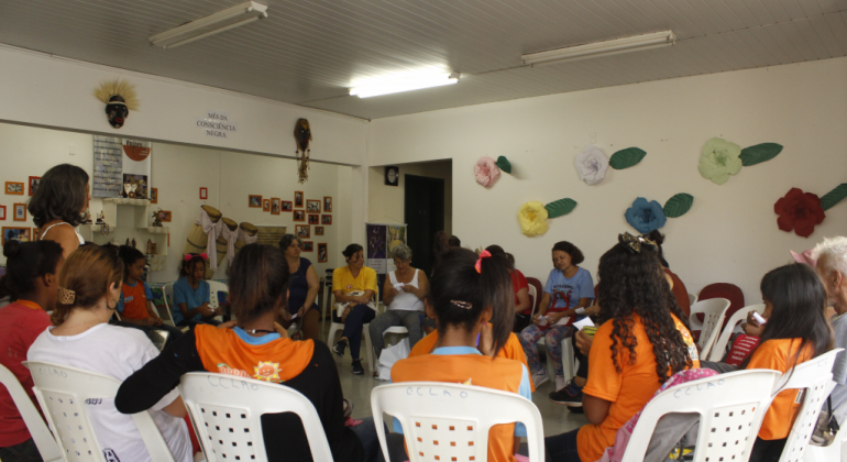 A Fundação Municipal de Cultura apresenta uma programação nos centros culturais em março, quando é comemorado o Dia Internacional da Mulher. Foto: Ruth Flores Cinco mulheres, sentadas assistem a Roda de Leitua em centro cultural.