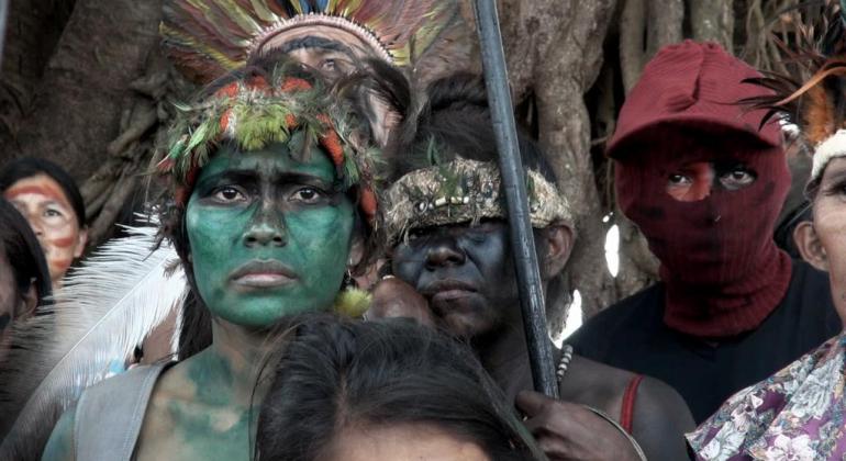 Homens com rostos pintados e armas na mão