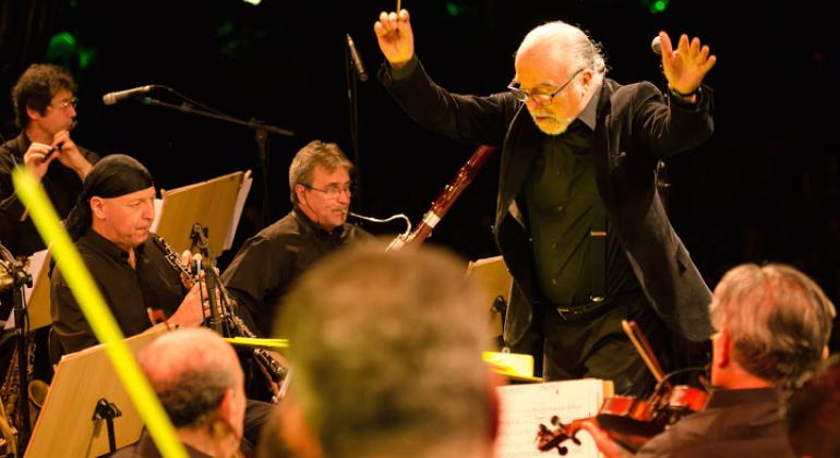 Maestro rege uma orquestra em um teatro.