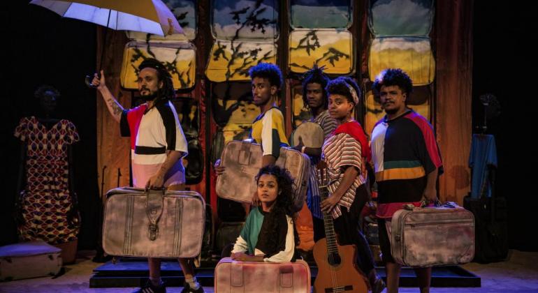 O FAN-BH tem Antonio Pitanga e filhos, Lira Ribas com homenagem a Marku, releituras Negras de Medeia, Gota D’agua e Navalha na Carne. Foto: O Bonde Coletivo Seis pessoas com malas parecem caminhar em ambiente teatral.