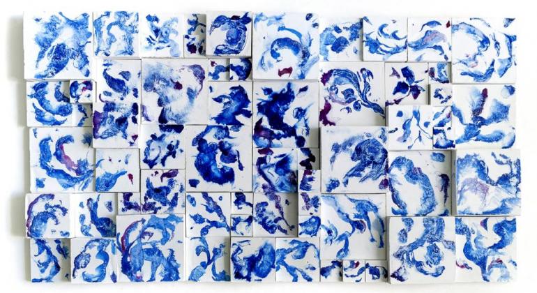 Obra de arte abstrata retangular, composta de mais de trinta quadrados pequenos, de tamanhos diferentes, dispostos em vários níveis de relevos, com fundo brando e pintados de vários tons de azul. 