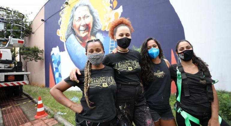 Grafiteiras em frente ao mural "Nós podemos tudo"