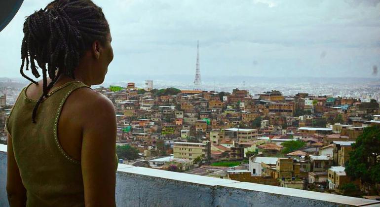 Mulher negra olhando a paisagem do Aglomerado da Serra