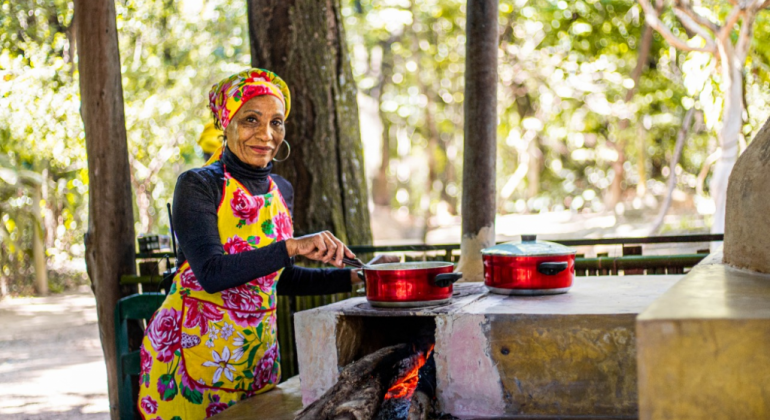Mulher cozinhando em um fogão à lenha