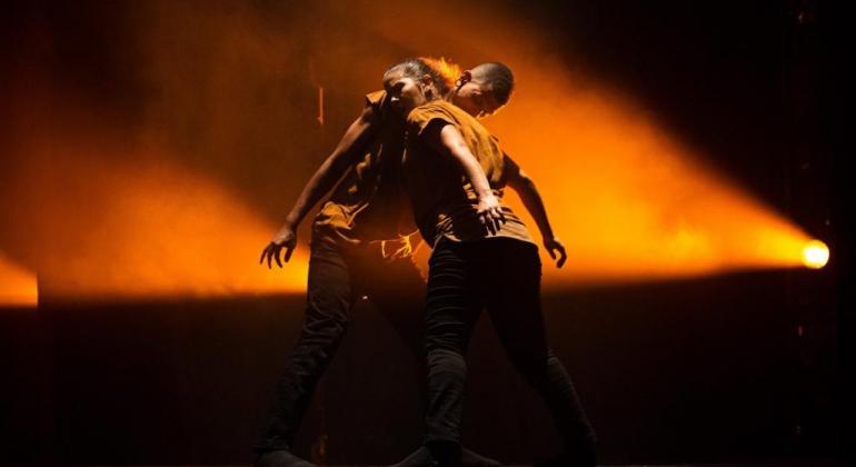 Residência CRDançaBH leva espetáculos e filmes para o público do Terça da Dança Dançarinos negros se apresentam sendo iluminados por um luz amarela sobre fundo preto