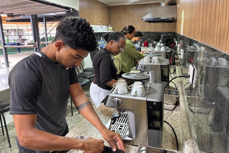 Curso de barista promovido pela PBH amplia oportunidades no mercado do café Jovens participam de atividade prática de preparação de café, utilizando máquinas de expresso em um espaço de formação profissional. Durante a atividade, os participantes manuseiam equipamentos e utensílios, desenvolvendo habilidades relacionadas ao preparo e ao serviço de bebidas.