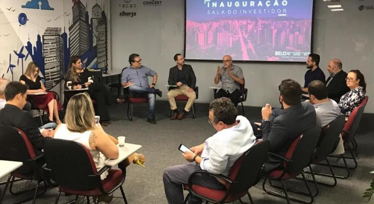 Foto: Divulgação PBH Cerca de vinte participantes sentados em cadeiras agrupadas em forma circular; ao fundo, um painel de vídeo.