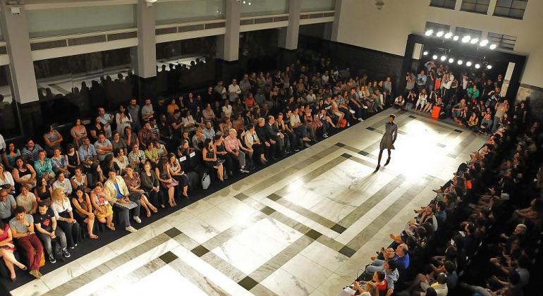 Modelo desfila no saguão da Prefeitura de Belo Horizonte. Plateia de cerca de 500 pessoas assistem ao desfile.