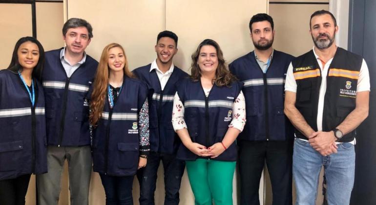Procon Municipal intensifica fiscalização contra a oferta de empréstimos abusivos no Dia do Idoso. Foto: Divulgação PBH Sete membros da equipe do Procon Municipal, de pé, posam para foto.
