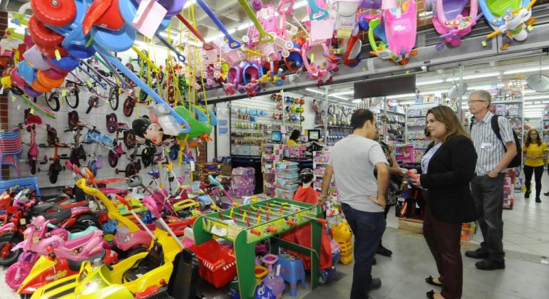 Procon realiza fiscalização em lojas para o Dia das Crianças Em loja de brinquedos infantis, mulher conversa com lojista