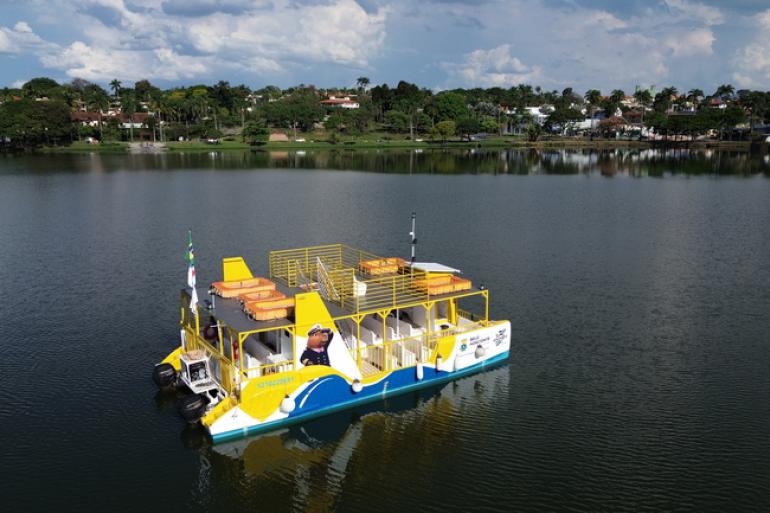 Navegação turística na Lagoa da Pampulha será retomada com o Capivarã neste sábado (10) Barco turístico, nas cores branco, azul e amarelo, navegando na Lagoa da Pampulha, mostrando a orla ao fundo
