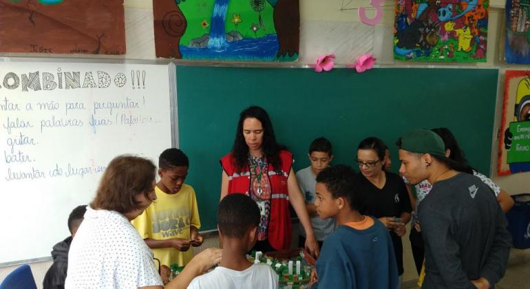 Alunos e professoras em sala de aula em volta de uma maquete