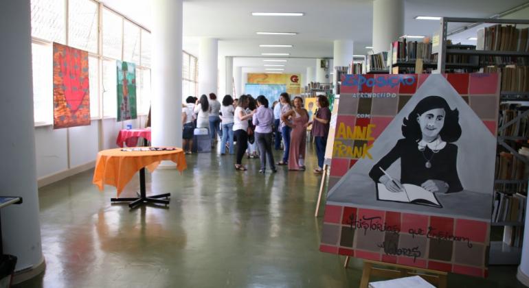 Biblioteca do Professor recebe exposição sobre Anne Frank Foto de um cartaz da exposição com a biblioteca ao fundo