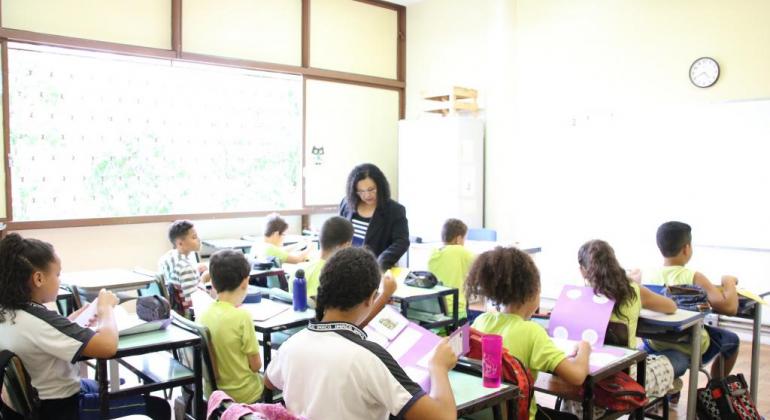 Foto de uma sala de aula repleta de crianças e professora ensinando matemática por meio do projeto